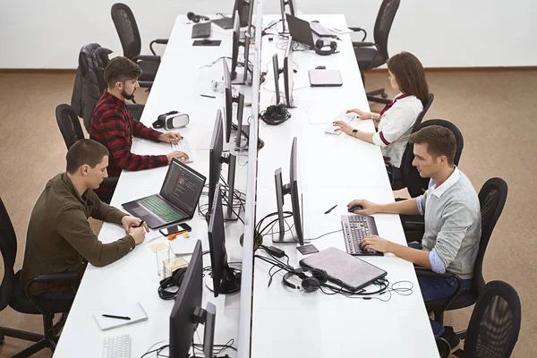 Modern ofiste çalışan genç profesyoneller. IT şirketinin açık alanındaki bilgisayarlara odaklanmış bir grup geliştirici ya da programcı. Ekip iş başında. Yüksek kaliteli resim.