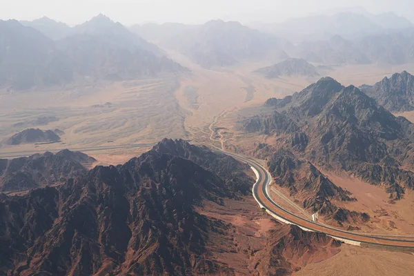 Vue aérienne d'une route tournant entre des montagnes rocheuses sans arbres et le désert au sud de la péninsule du Sinaï près de Sharm El Sheikh — Photo