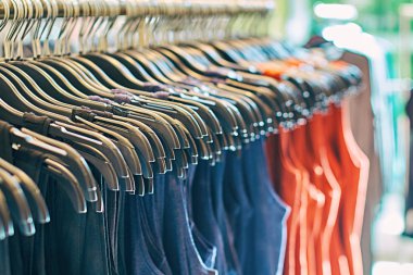 Kırmızı, mavi ve diğer renklerde askıları üzerinde farklı kadın giysileri ile moda giyim mağazası Iç.