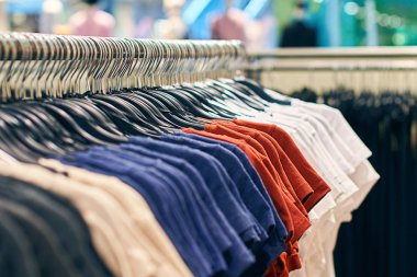 Kırmızı, mavi ve diğer renklerde askıları üzerinde t-shirt ile moda giyim mağazası Iç.