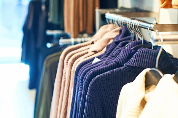 Suéteres de jersey de mujer en diferentes colores en perchas en una tienda de ropa al por menor . — Foto de Stock