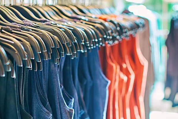 Interior de la tienda de ropa de moda con diferentes ropa de mujer en perchas en rojo, azul y otros colores . — Foto de Stock