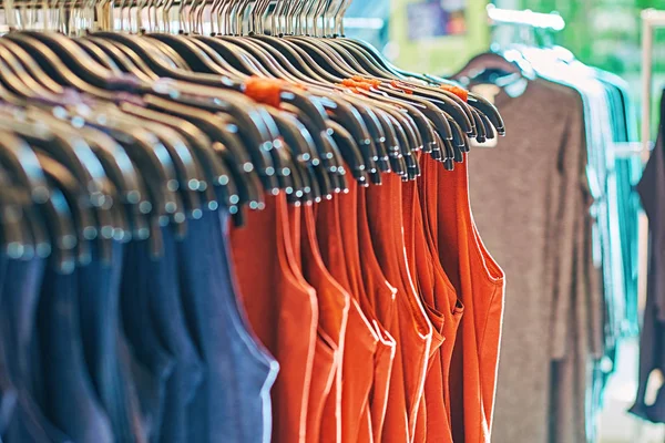 Interior divat ruházati bolt különböző női ruhát akasztók piros, kék és egyéb színek. — Stock Fotó