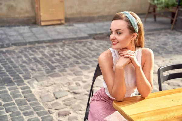 Junge schöne Mädchen im Retro-Vintage-Stil gekleidet in der alten europäischen Stadt sitzt auf der Straße Café Holztisch — Stockfoto