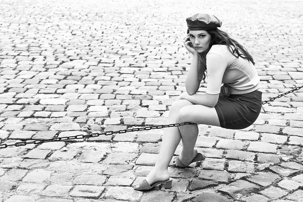 Joven hermosa morena emocional chica vestida en estilo retro vintage en la vieja ciudad europea se sienta de una cadena — Foto de Stock