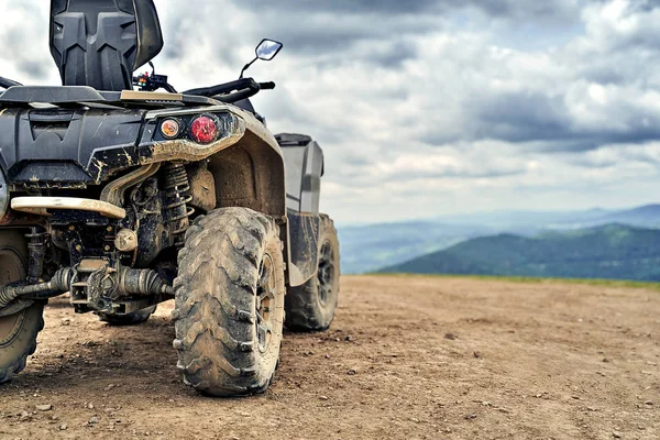 Quadricycle or quad bike on the mountains background on a cloudy day