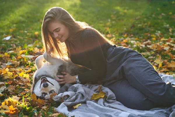 Mladá krásná dívka si zahrává s roztomilým psím psem v podzimním parku pokrytých červenými a žlutými padýma listy — Stock fotografie