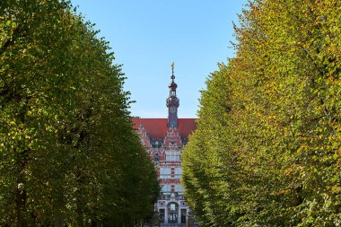 Gdansk Teknoloji Üniversitesi'nin ana binası veya Politechnika Gdanska yaklaşan sokaktaki ağaçlar arasında