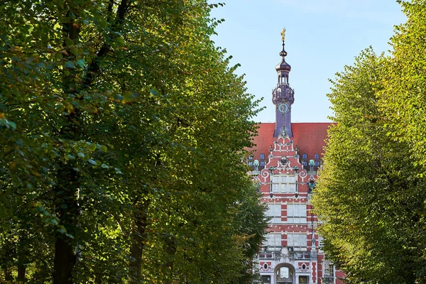 El edificio principal de la Universidad Tecnológica de Gdansk o Politechnika Gdanska entre los árboles en el callejón que se aproxima — Foto de Stock
