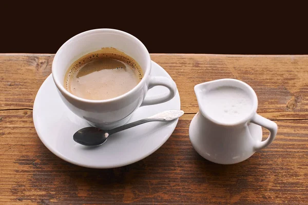 Seramik bardakta sütlü kahve eski ahşap pencere pervazında küçük süt sürahisi — Stok fotoğraf