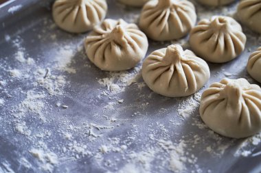 Ev yapımı çiğ khinkali yığını. Lezzetli Gürcü köfteleri. Mutfak masasında.