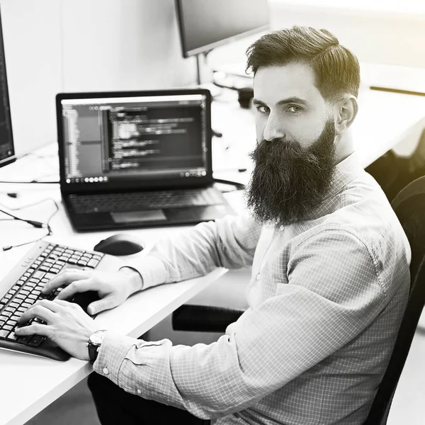 Serious computer programmer developer working in IT office, sitting at desk and coding, working on a project in software development company or startup. Black and white, — Stock Photo, Image