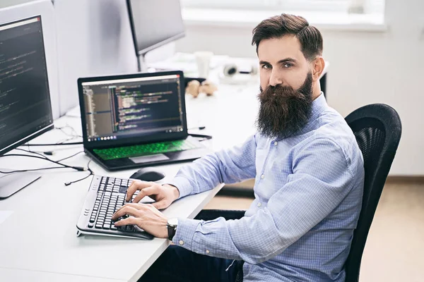 IT ofisinde çalışan ciddi bir bilgisayar programcısı, masa başında oturuyor ve kodluyor, yazılım geliştirme şirketinde ya da başlangıçta bir proje üzerinde çalışıyor..