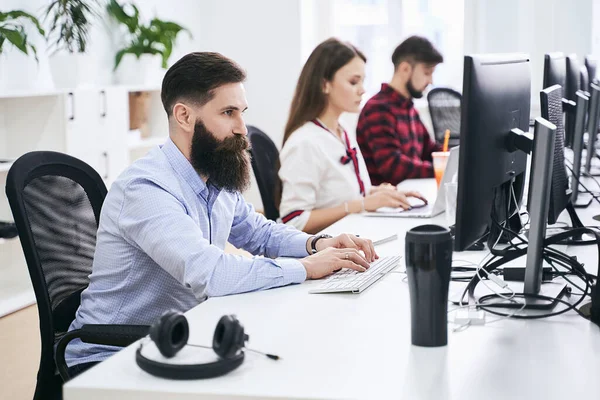 People working in modern IT office. Group of young and experienced programmers and software developers sitting at desks working on computers. Team at work. High quality image. — Stock Photo, Image