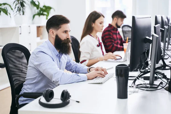 Modern bilişim ofisinde çalışan insanlar. Bir grup genç ve deneyimli programcı ve yazılım geliştirici bilgisayar üzerinde çalışıyor. Ekip iş başında. Yüksek kaliteli resim.