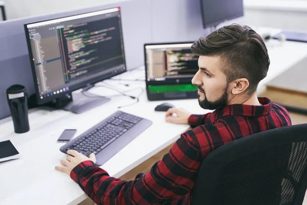 Software developer working on computer in IT office, sitting at desk and coding, working on a project in software development company or technology startup. High quality image. — Stock Photo, Image