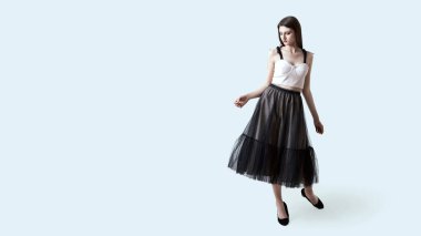 Siyah kutulu, pileli etekli esmer kız stüdyoda poz veriyor. Dans eden ya da adım atan bir kadın.