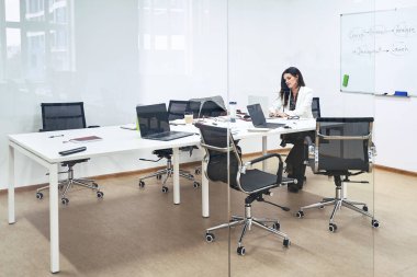 Modern ofiste tek başına düşünceli, kendine güvenen, beyaz bir iş kadını ya da yönetici. Bayan bir yazılım geliştirme şirketinin toplantı odasında oturuyor..