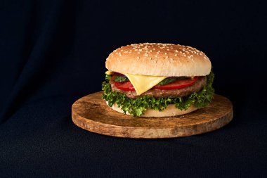 Siyah arka planda izole edilmiş ahşap kesme tahtasındaki leziz klasik burger.
