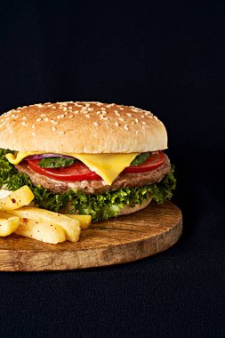 Siyah arka planda izole edilmiş ahşap kesme tahtasındaki leziz klasik burger.