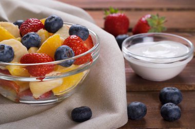 Cam plaka üzerinde koyu ahşap, stil rustik meyve salatası. Çilek, yaban mersini, muz ve portakal karışımı.