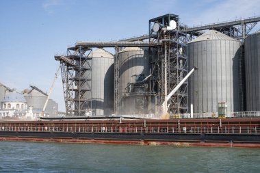 Limandaki bir gemiye tahıl yüklüyor. Nehirden liman altyapısına, tahıl depolama terminallerine görünüm