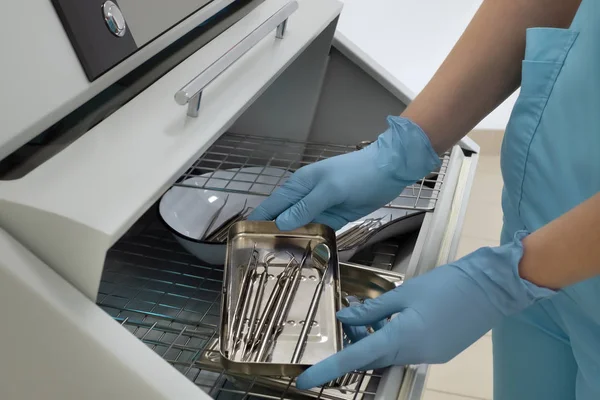 Sterilizatörden diş aletleri seti alan diş hekiminin yakın çekimi.