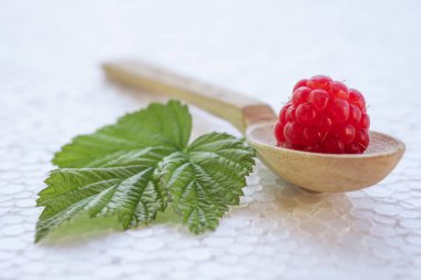 Ahududu olan tahta bir kaşıkta. Yeşil yaprak yakın.