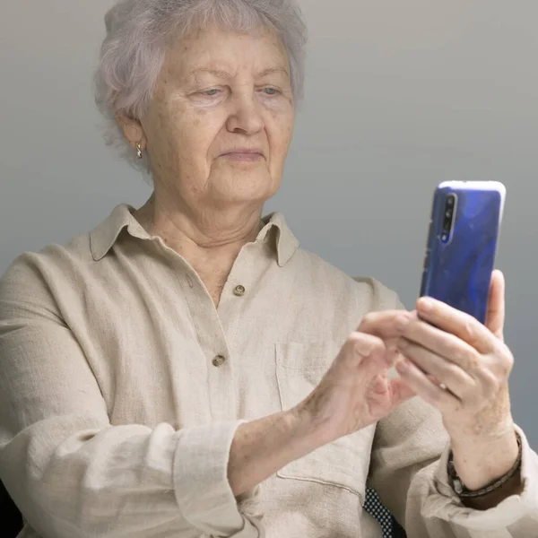 Happy elderly woman on the phone. Pensioner holding smartphone. An elderly lady takes selfie. — Stock Photo, Image