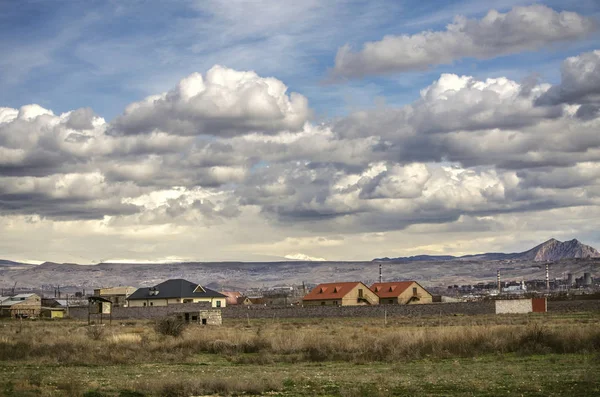 Inizio primavera nella capitale armena Erevan, sobborgo di Nerkin Charbakh con case residenziali, vista sulle montagne e il cielo coperto di nuvole di pioggia — Foto Stock