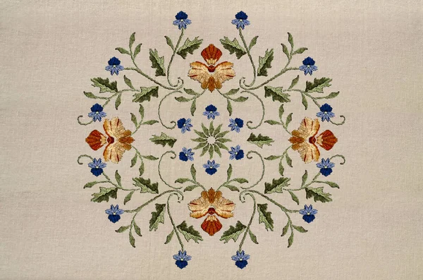 Κέντημα στρογγυλό μοτίβο με κόκκινα-κίτρινα λουλούδια και μπλε λουλούδια σε στριμμένα κοτσάνια με φύλλα στο κάλο — Φωτογραφία Αρχείου