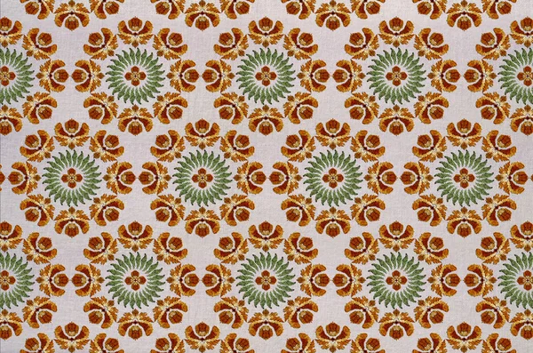 Background on cotton fabric of round embroidery with stylized orange flowers, wreath of green leaves and a flower in the center — Stock Photo, Image