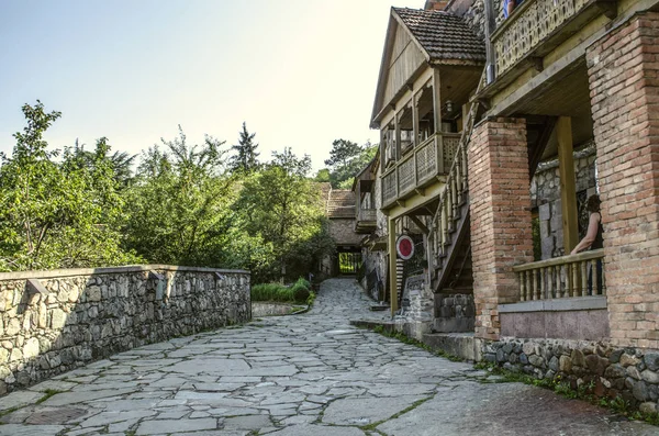 Callejón estrecho con casas antiguas de piedra rugosa y columnas de ladrillo, con balcones tallados en madera en el Museo Tufenkian Old Dilijan — Foto de Stock