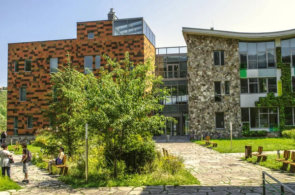 Vista desde el jardín hasta el pasillo acristalado que conecta los edificios administrativos y educativos del Colegio Internacional de Dilijan, rodeado de bosques —  Fotos de Stock