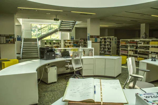 Utrymme mellan flygningar av trappor, reserverade för biblioteket med bokhyllor, oval bord för tullen vid International College i Dilijan — Stockfoto