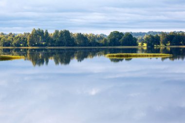 Bir göl, mükemmel yansıma, bulutlar ve orman