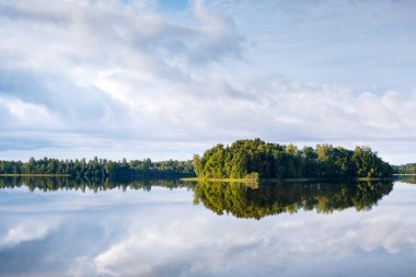 Bir göl, mükemmel yansıma, bulutlar ve orman