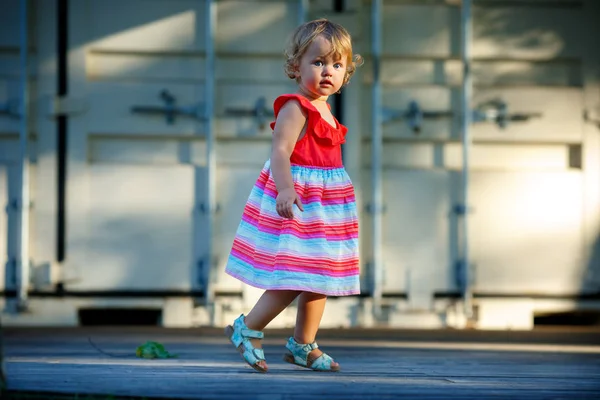 Söt blond liten baby flicka i vacker klänning spelar promenader utomhus — Stockfoto