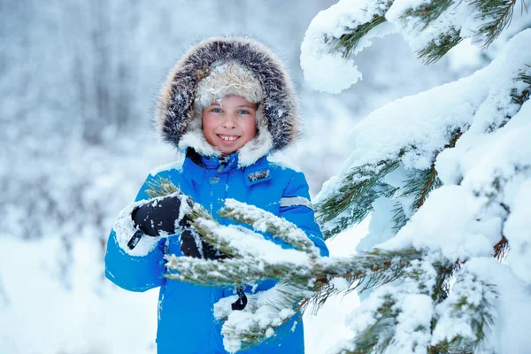 Cute little boy wearing warm clothes playing on winter forest — Stock Photo, Image