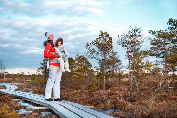 Junge Mutter mit ihrer kleinen Tochter im Tragetuch draußen auf Wanderwegen im Sumpf, Kemeri-Nationalpark, Lettland — Stockfoto