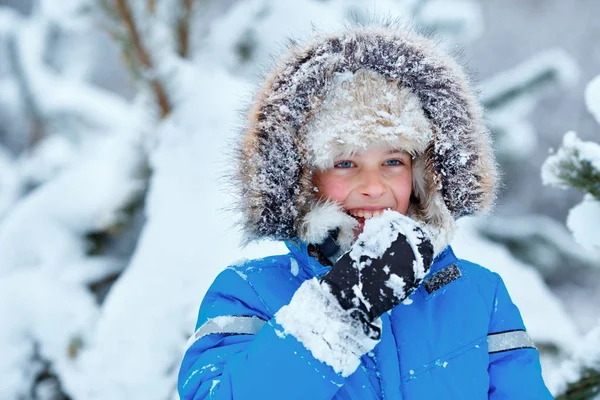 Söt liten pojke som bär varma kläder spelar på vintern skog — Stockfoto