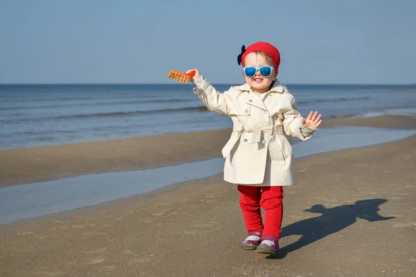 Lycklig liten flicka körs på Östersjöns strand i Lettland. Barnen leker i havet sanddyner på kalla höst eller vår — Stockfoto