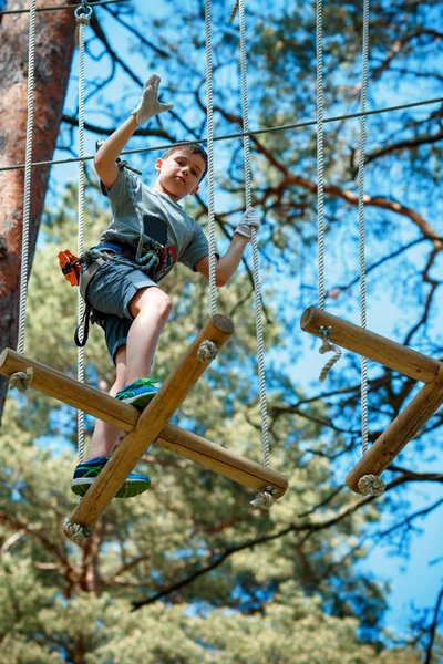 Bonito menino desfrutando de seu tempo no parque de aventura de escalada — Fotografia de Stock