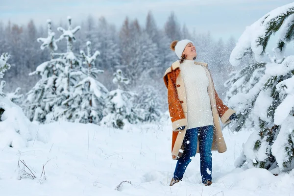 Mujer embarazada joven que usa ropa de abrigo que se divierte en el bosque de invierno — Foto de Stock