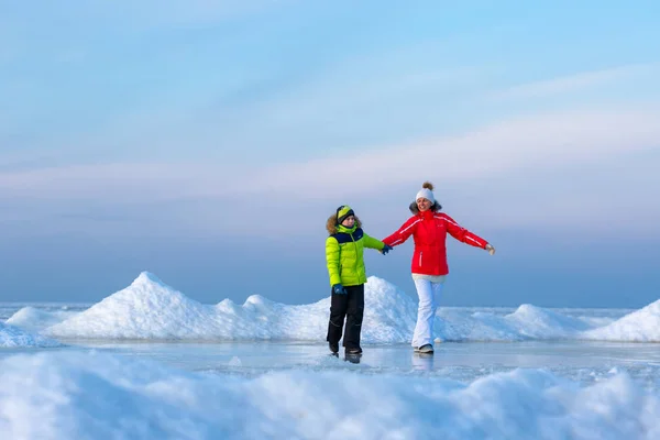 Giovane madre e suo figlio sulla spiaggia ghiacciata — Foto Stock
