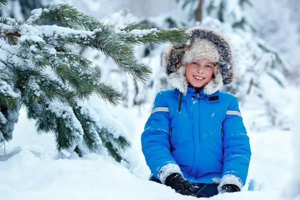 Söt liten pojke som bär varma kläder spelar på vintern skog — Stockfoto