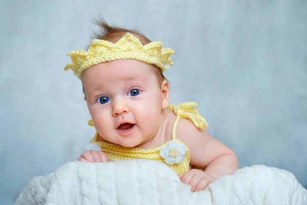 Портрет милої новонародженої дівчинки в жовтій в'язаній короні, що лежить на животі — стокове фото