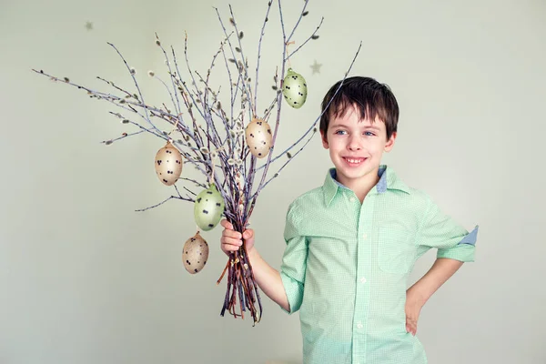 Lindo niño sosteniendo ramitas de sauce coño con huevos de Pascua colgantes — Foto de Stock