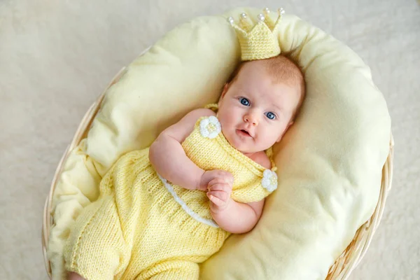 新生女婴躺在金色的皇冠和黄色紧身衣一篮子的肖像 — 图库照片