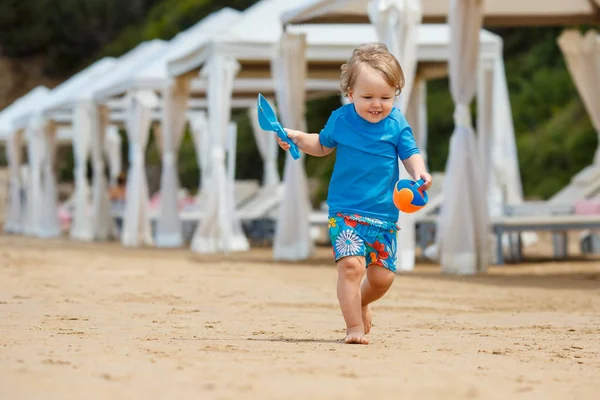 Dítě hrající na tropické pláži. Malá dívka kopání písku, shore na moři. Děti si hrát s hračkami na písek. Cestování s malými dětmi — Stock fotografie
